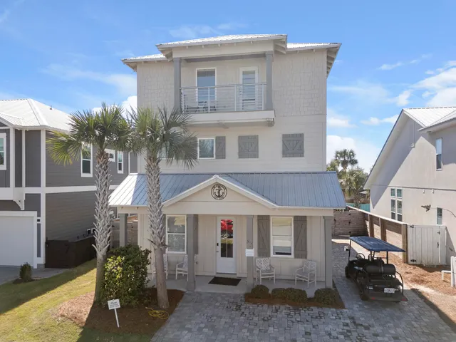 a view of a white house with a yard and table and chairs under an umbrella