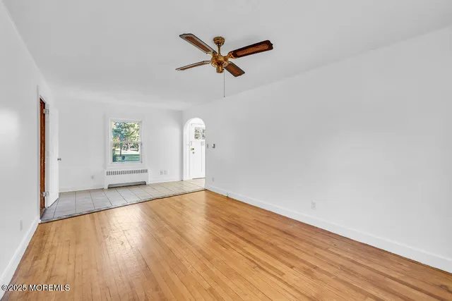 a view of empty room with wooden floor and ceiling fan