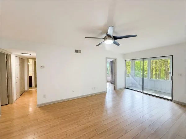 a view of an empty room with a window and wooden floor