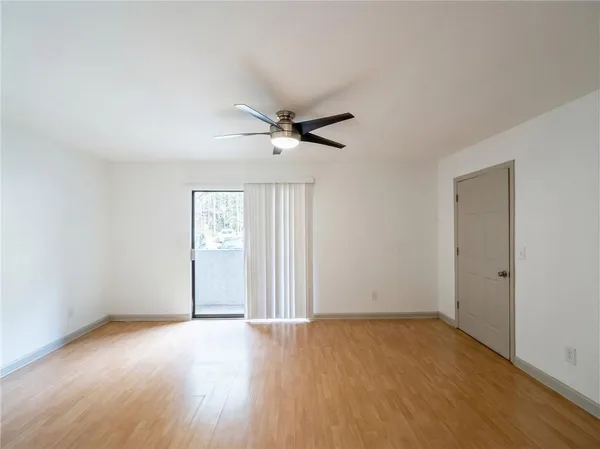 an empty room with wooden floor and ceiling fan