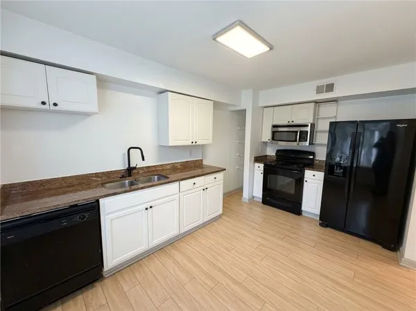 a kitchen with a refrigerator cabinets and wooden floor