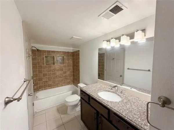 a bathroom with a granite countertop sink a toilet a mirror and shower