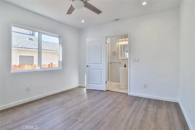 an empty room with wooden floor cabinet and windows