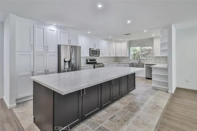 a kitchen with stainless steel appliances a sink a stove a refrigerator and cabinets