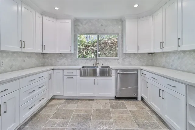 a kitchen with white cabinets and window