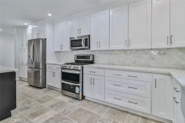 a kitchen with white cabinets and stainless steel appliances