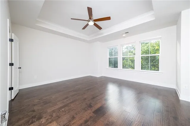 an empty room with wooden floor and ceiling fan