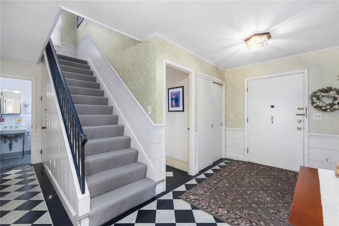 2 Lansdowne Road Warwick, RI 02888 - Photo 23 of 49 A view of the stairs leading up to the second level shows the entire foyer, the first floor office and the first floor half bath. Original, shiplap style wainscoting leads from the first floor up to the second level.