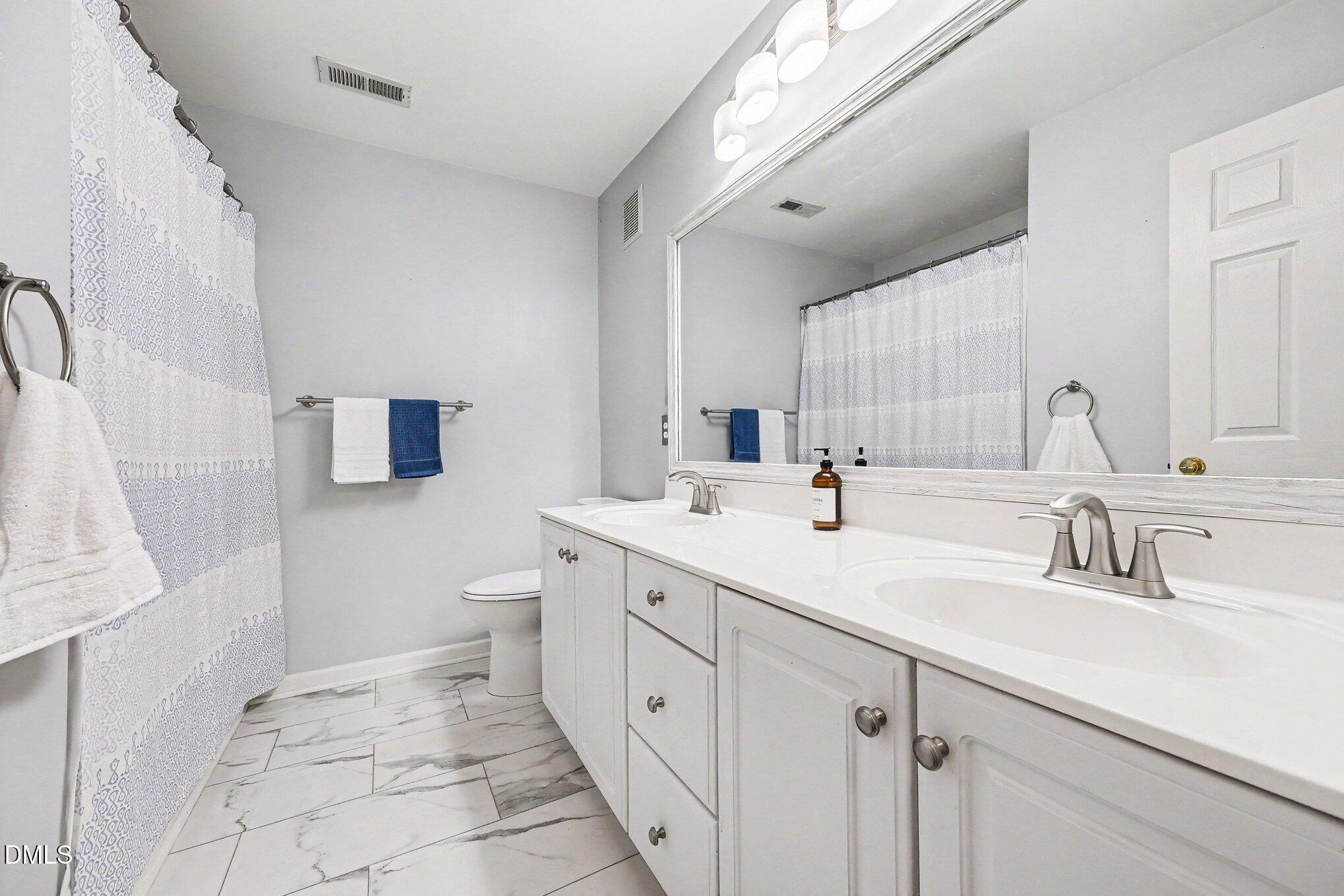 132 Springfork Drive Cary, NC 27513 - Photo 23 of 28 a spacious bathroom with a double vanity sink mirror and toilet