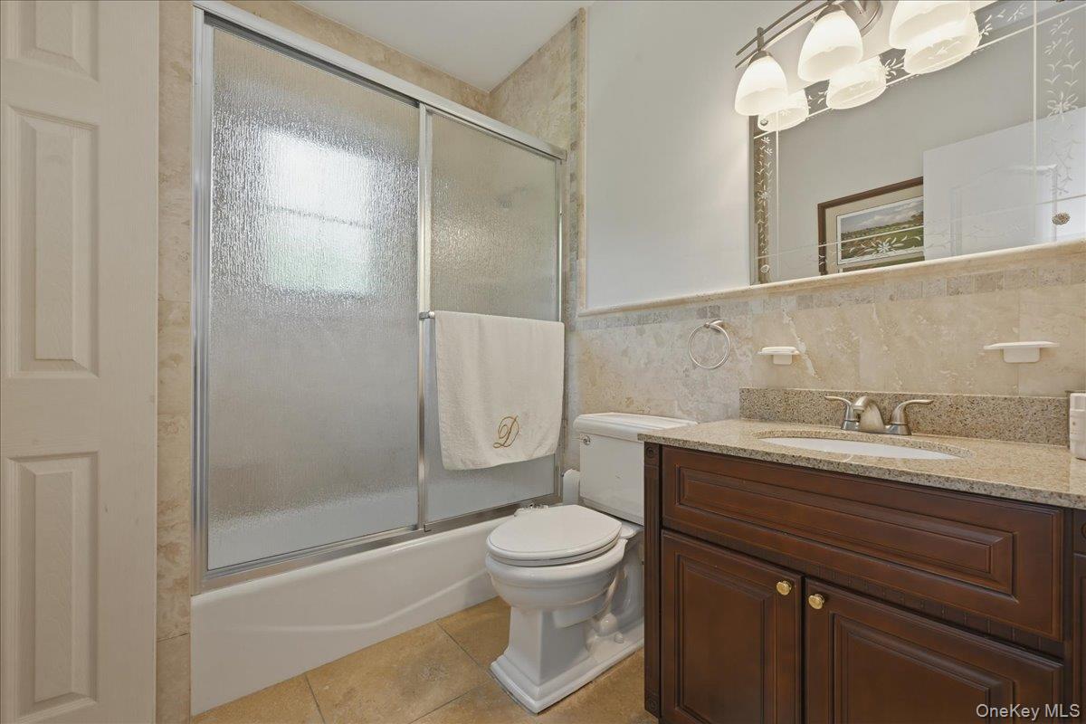 31 Cornwall Lane Sands Point, NY 11050 - Photo 32 of 49 a bathroom with a granite countertop sink a toilet and shower