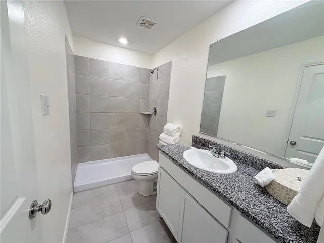 a bathroom with a granite countertop sink a toilet and shower