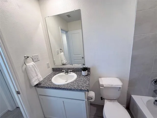 a bathroom with a granite countertop sink toilet and mirror