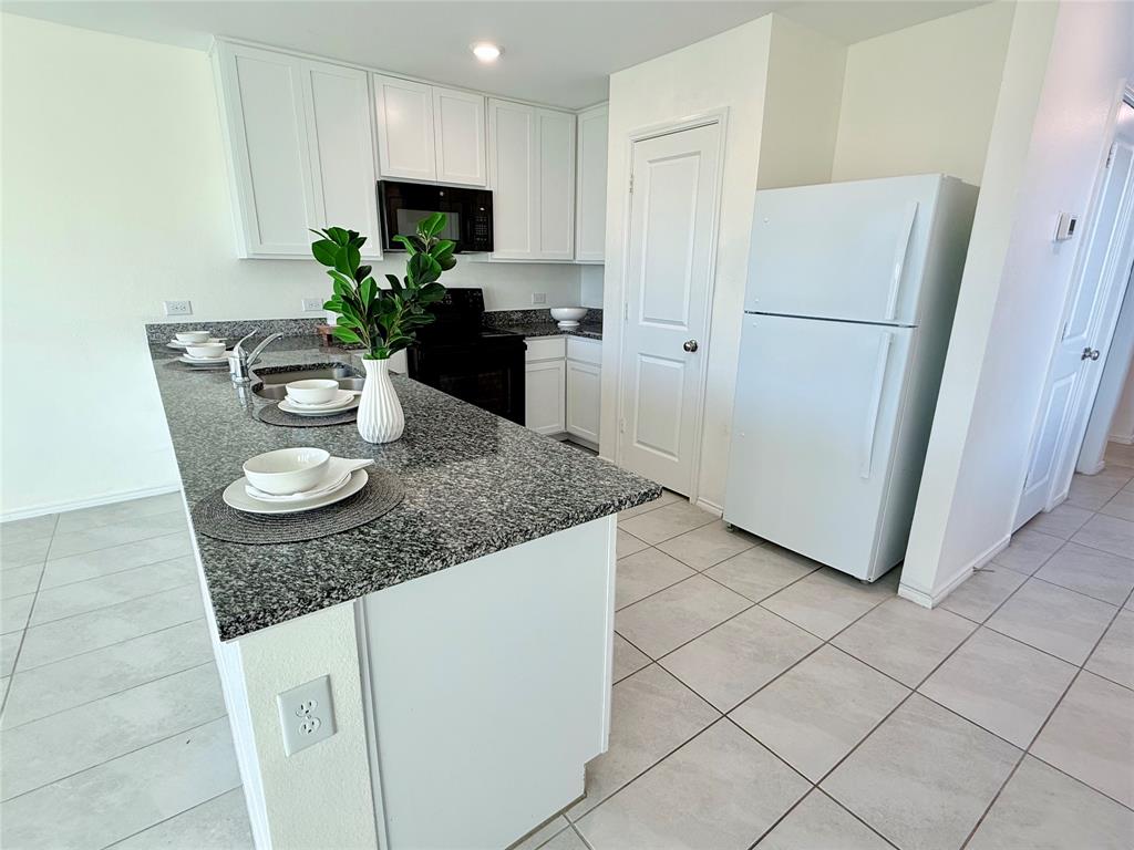 201 Boxberry Way Princeton, TX 75407 - Photo 4 of 24 a kitchen with stainless steel appliances granite countertop a refrigerator a sink a microwave a stove and white cabinets