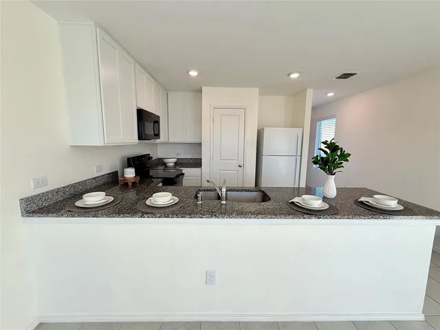 a kitchen with stainless steel appliances granite countertop a sink a microwave a refrigerator and a stove