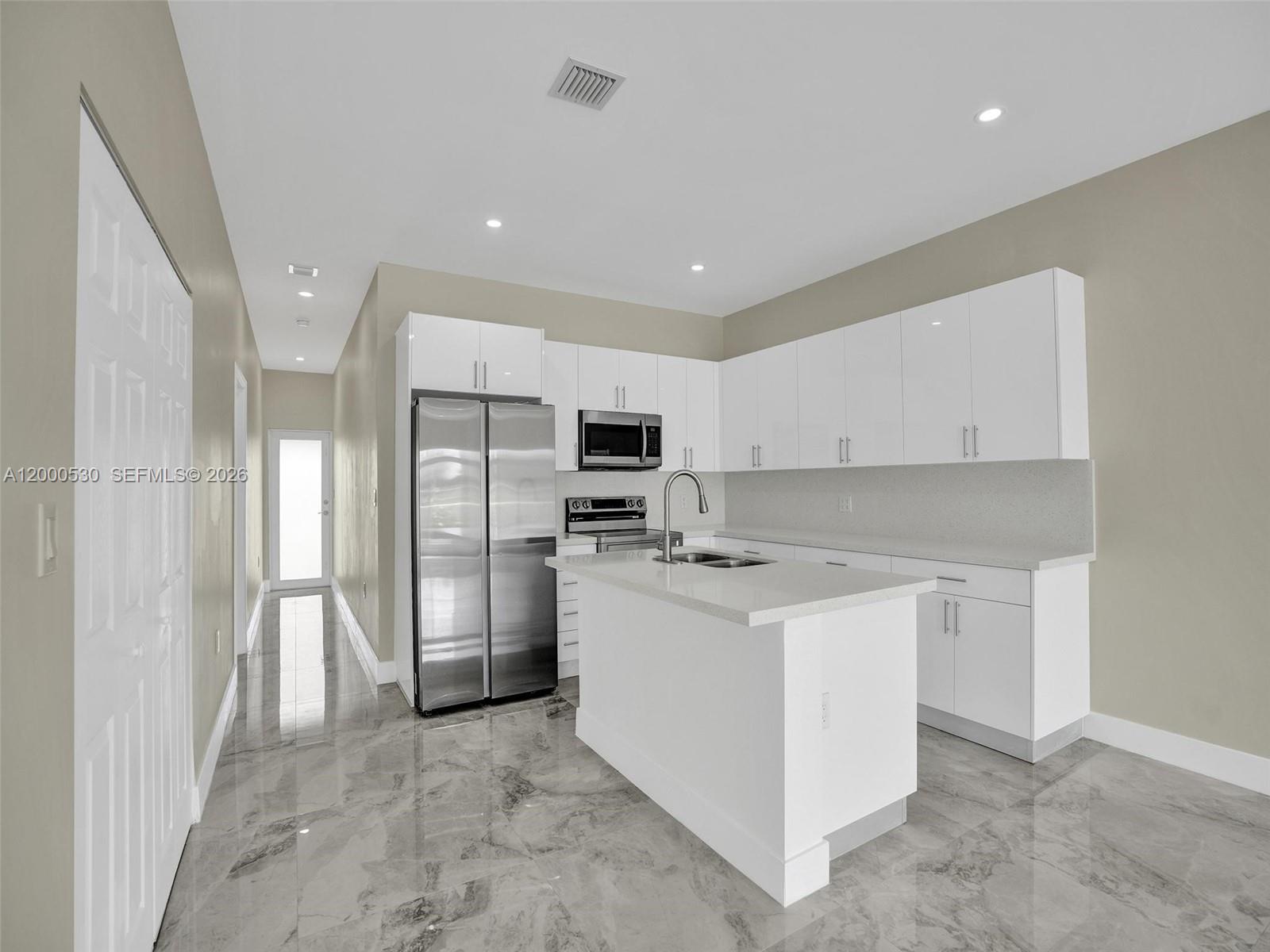 14519 Southwest 272nd Street, Unit 14519 Homestead, FL 33032 - Photo 6 of 32 a kitchen with stainless steel appliances a refrigerator stove microwave and cabinets