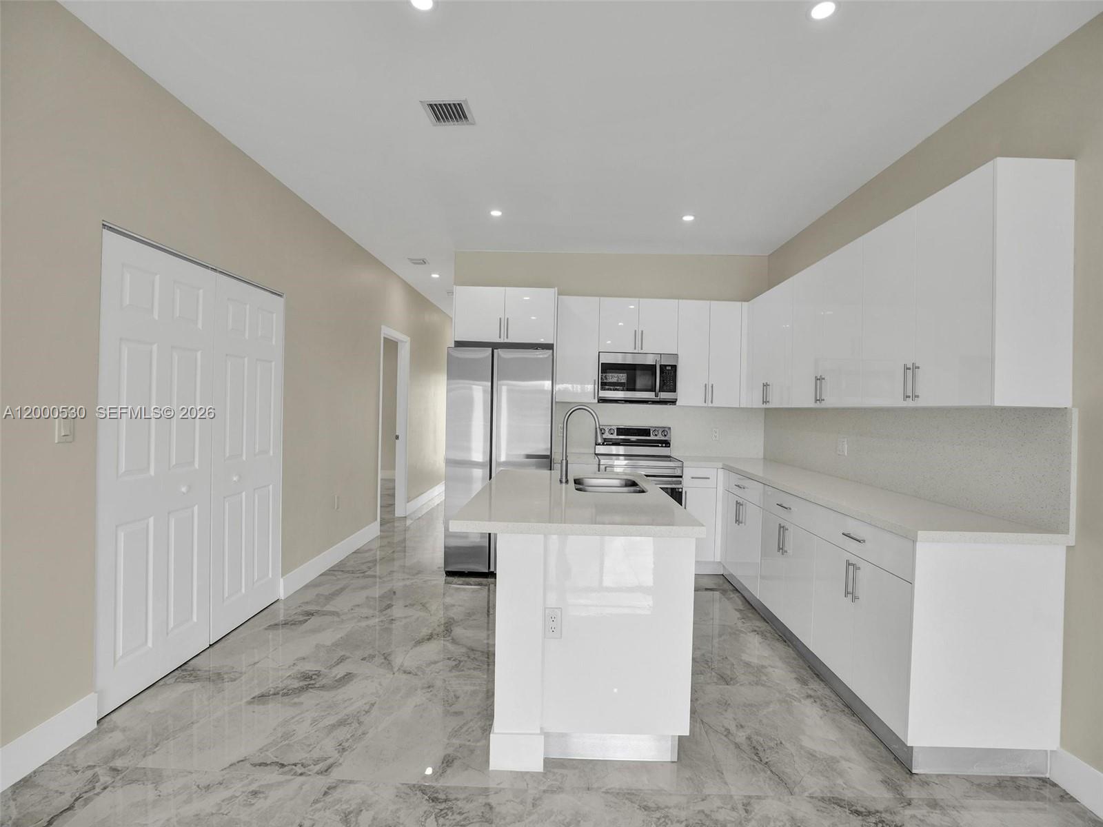 14519 Southwest 272nd Street, Unit 14519 Homestead, FL 33032 - Photo 7 of 32 a kitchen with stainless steel appliances kitchen island granite countertop a refrigerator and a stove top oven