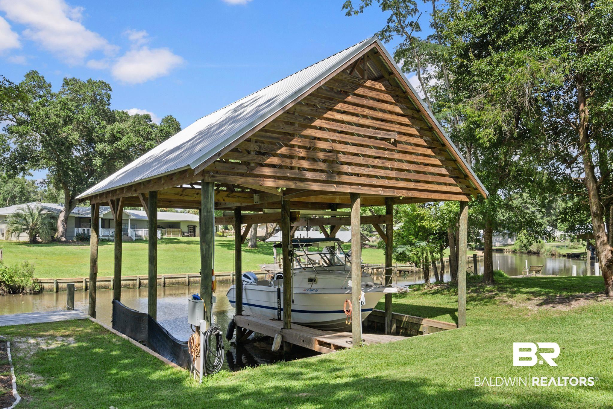 7266 Franklin Road Foley, AL 36535 - Photo 4 of 64 Covered boat dock featuring a metal roof, wood construction, electrical hookups, and direct water access