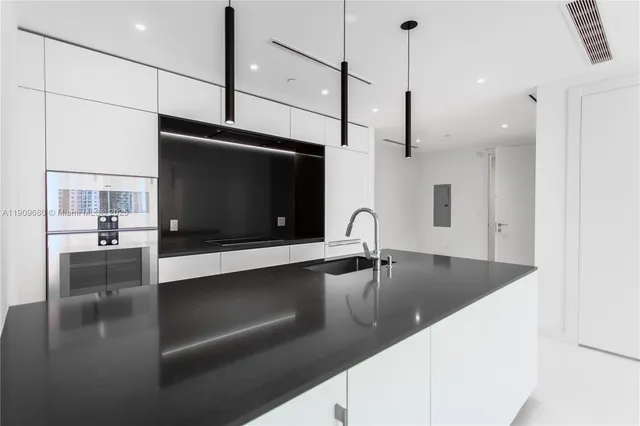 a view of a kitchen with kitchen island a sink appliances and a counter top space