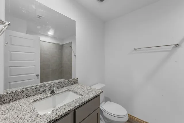 a bathroom with a granite countertop sink toilet a mirror and shower