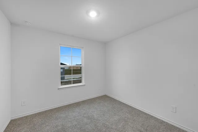 an empty room with a window and a kitchen