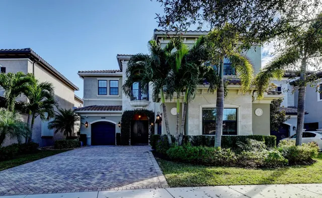 a view of a house with a yard and palm trees