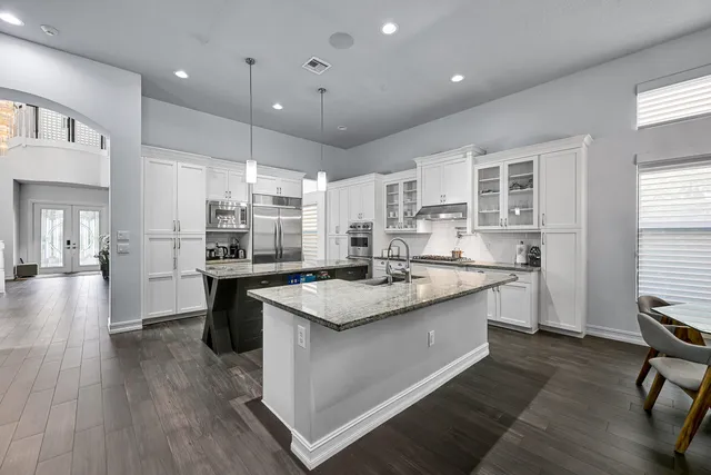 a open kitchen with stainless steel appliances granite countertop a sink dishwasher a dining table and chairs with wooden floor