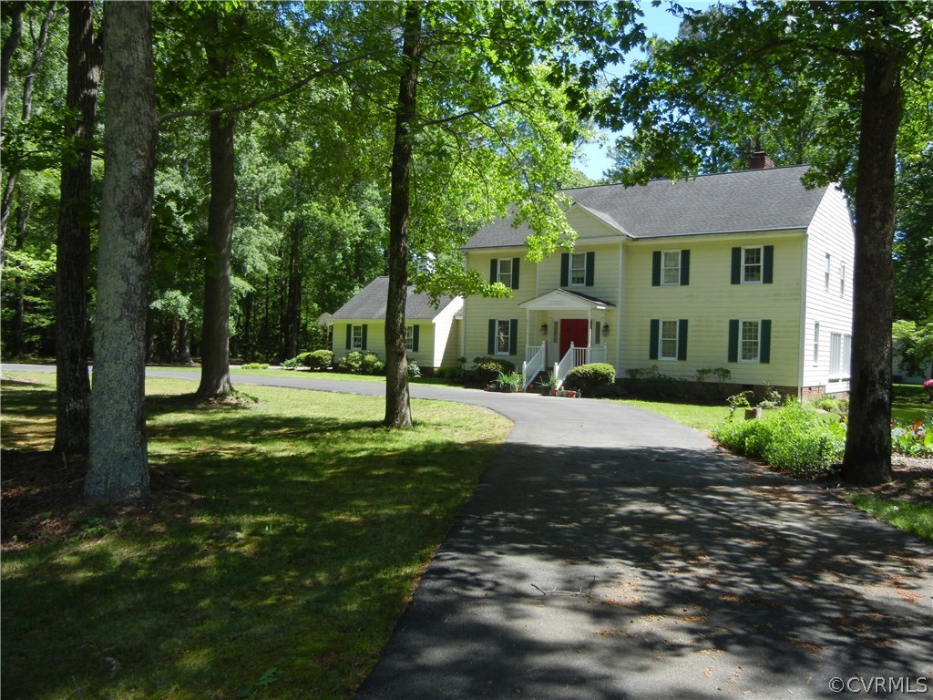 a view of a white house with a big yard and large trees