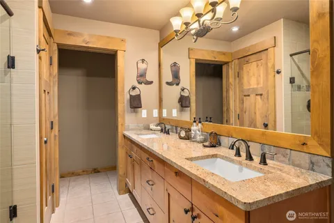 a bathroom with a granite countertop double vanity sink a mirror and a shower
