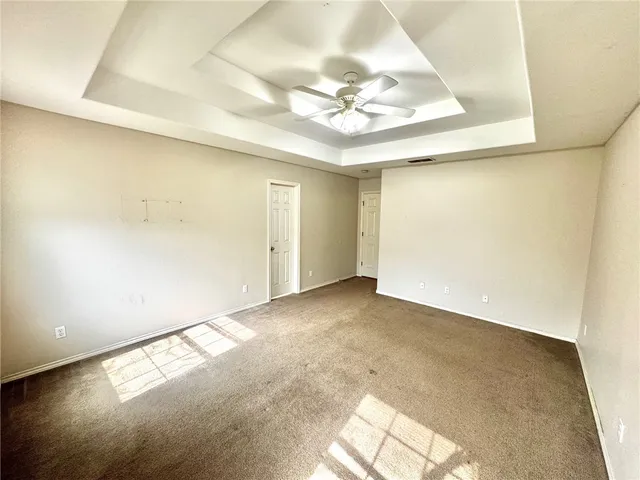 an empty room with a chandelier fan and windows
