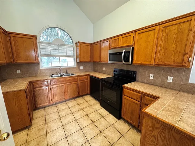 a kitchen with a sink a stove cabinets and a microwave