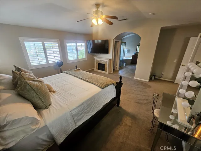 a spacious bedroom with a bed and a flat tv screen on dresser