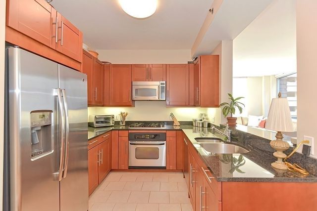 a kitchen with stainless steel appliances granite countertop a sink stove refrigerator and cabinets