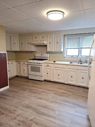 a kitchen with stainless steel appliances granite countertop a stove a sink and white cabinets