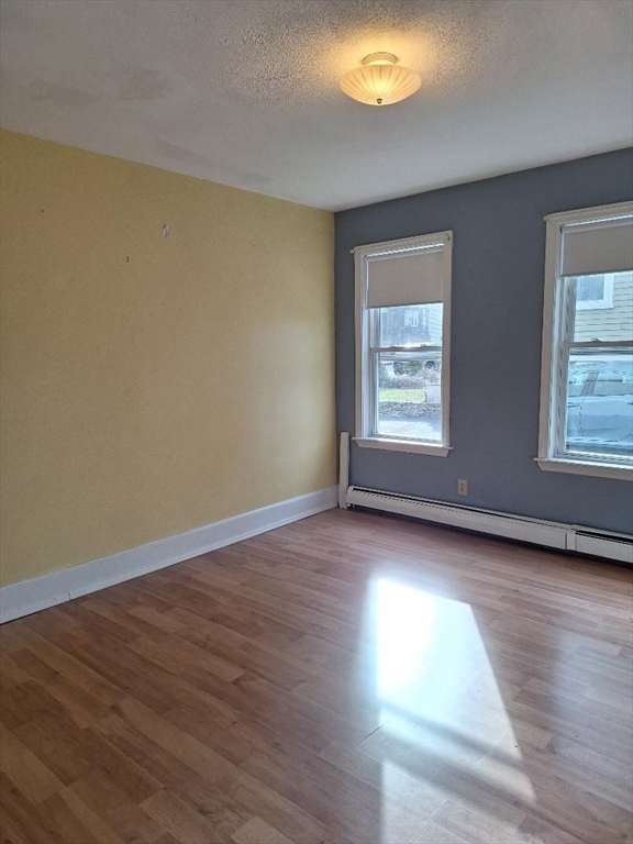 71 Adams Street, Unit 1 Medford, MA 02155 - Photo 5 of 7 a view of an empty room with wooden floor and a window