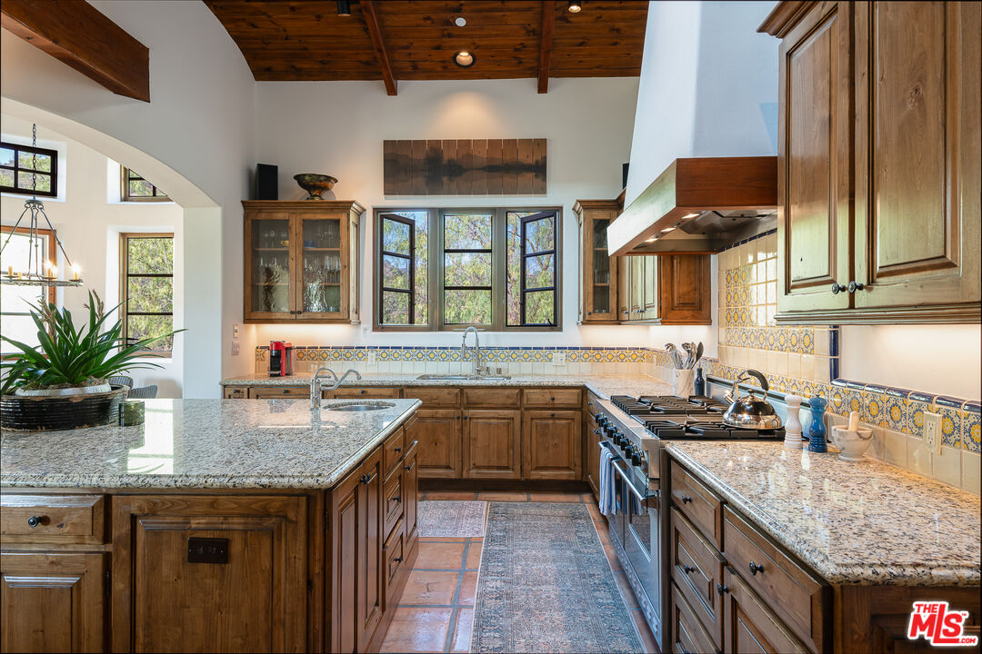 1101 Cold Canyon Road Calabasas, CA 91302 - Photo 12 of 60 a kitchen with a granite countertop sink stove and cabinets