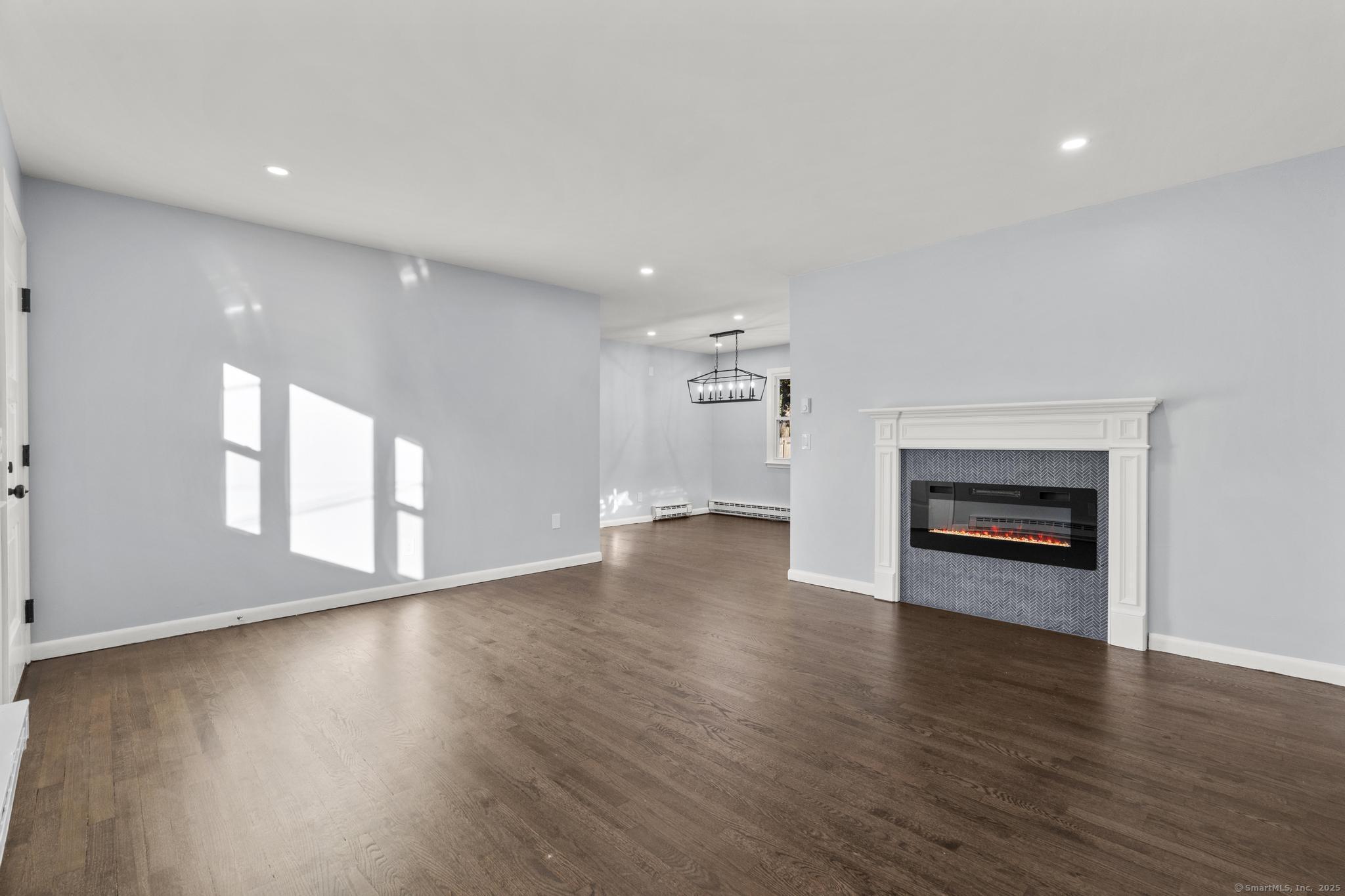 99 Roosevelt Avenue West Haven, CT 06516 - Photo 3 of 27 an empty room with wooden floor fireplace and windows