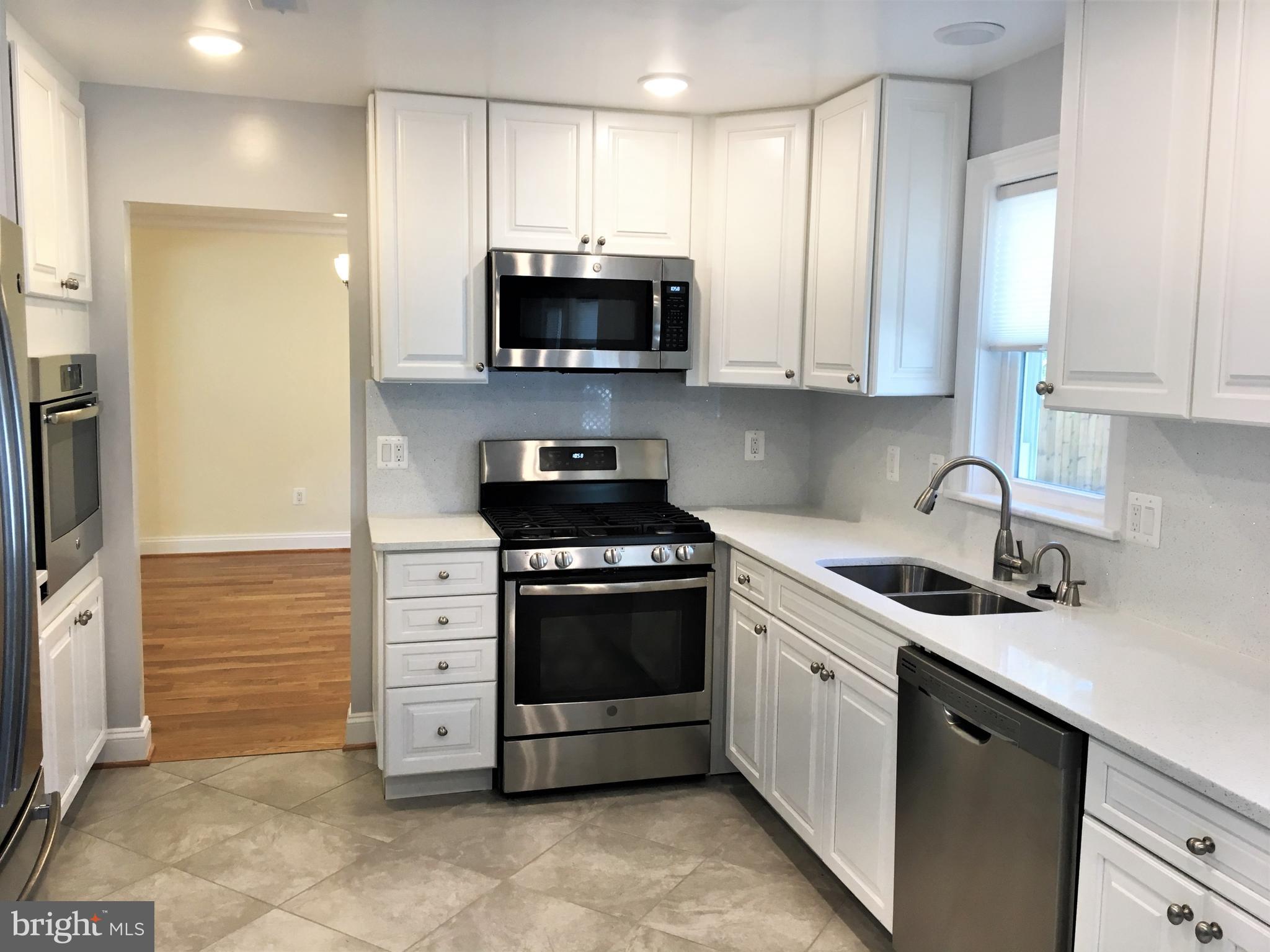 11514 Seven Locks Road Potomac, MD 20854 - Photo 5 of 72 a kitchen with stainless steel appliances granite countertop white cabinets a sink a stove a refrigerator and a microwave