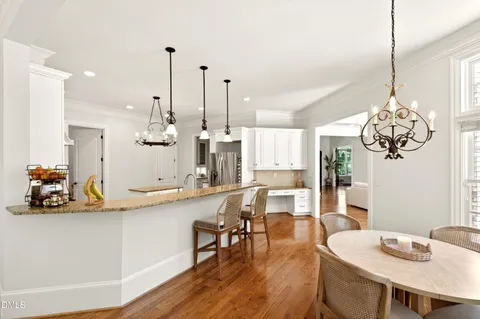 a view of a dining room and livingroom with furniture wooden floor a chandelier