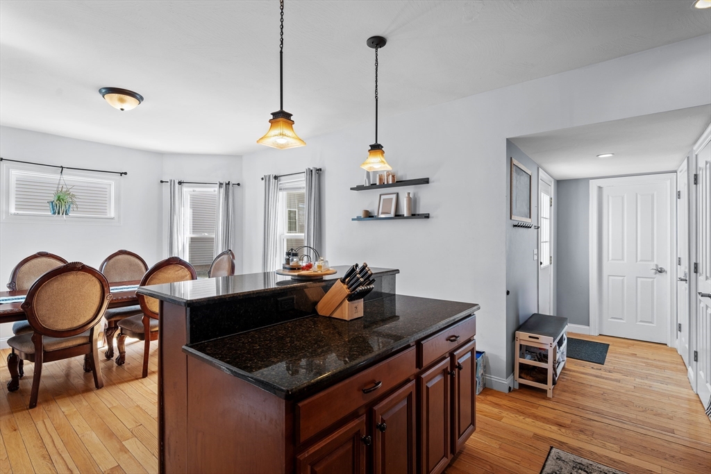 146 South Pleasant Street, Unit 146 Haverhill, MA 01835 - Photo 3 of 28 a kitchen with granite countertop a stove a sink a dining table and chairs with wooden floor