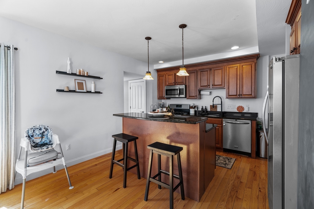 146 South Pleasant Street, Unit 146 Haverhill, MA 01835 - Photo 6 of 28 a kitchen with stainless steel appliances granite countertop a stove a sink a refrigerator and a wooden floor