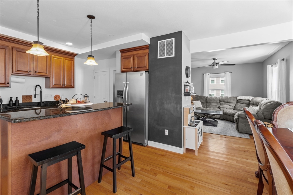 146 South Pleasant Street, Unit 146 Haverhill, MA 01835 - Photo 9 of 28 a kitchen with stainless steel appliances granite countertop a refrigerator a sink dishwasher a stove and white countertops with wooden floor