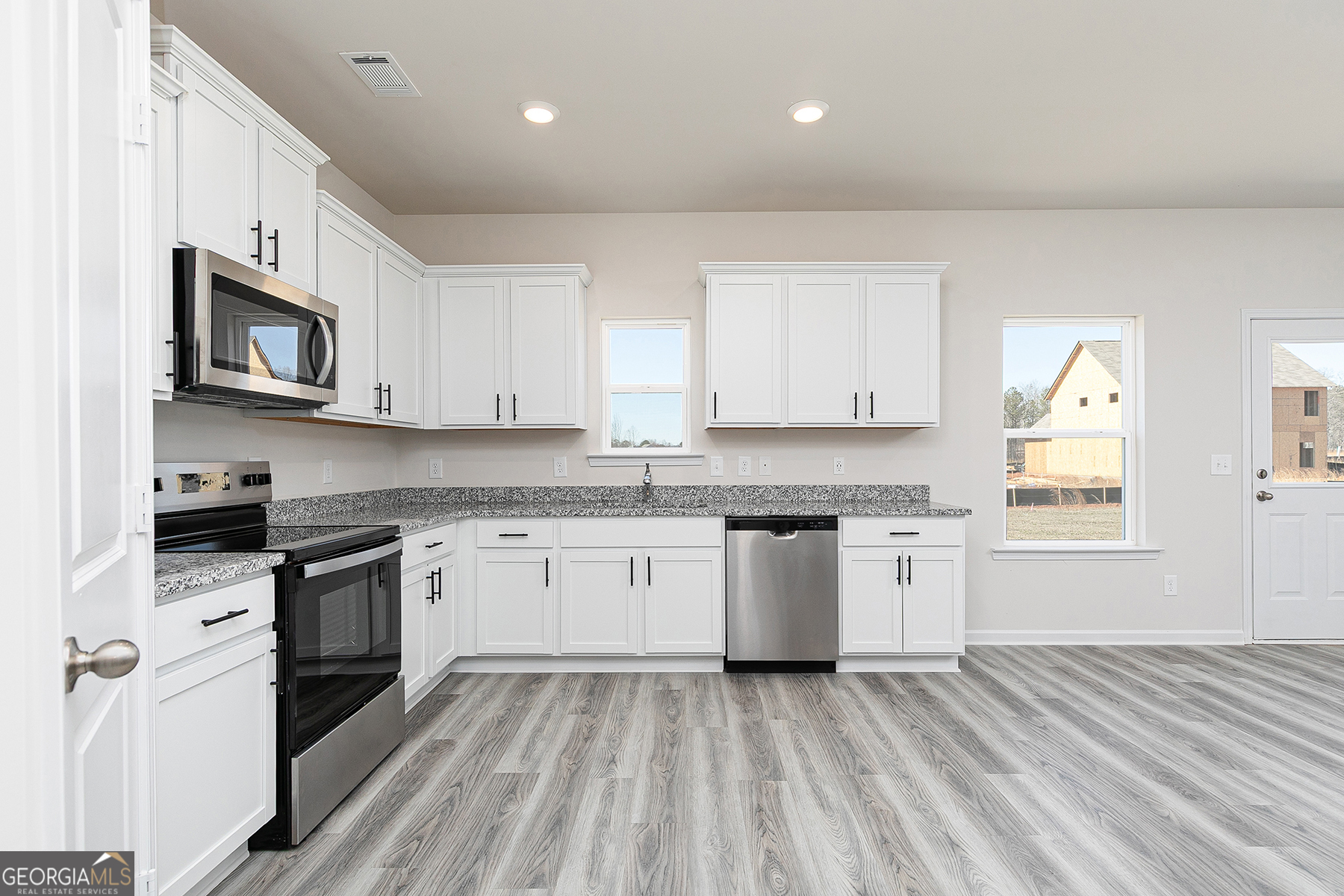 661 Mackenzie Cove Villa Rica, GA 30180 - Photo 8 of 18 a kitchen with granite countertop white cabinets a sink a window and stainless steel appliances