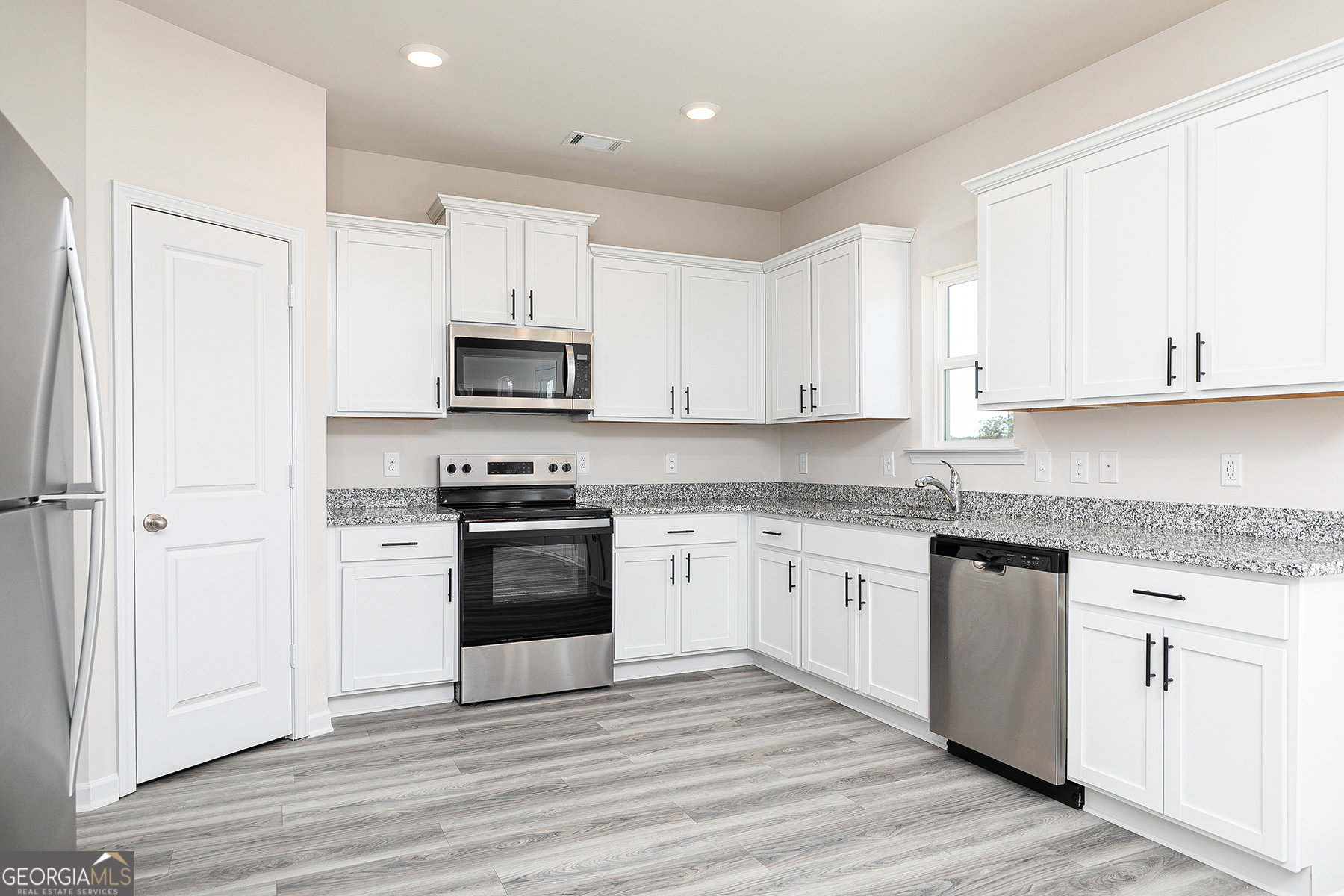 661 Mackenzie Cove Villa Rica, GA 30180 - Photo 9 of 18 a kitchen with granite countertop white cabinets and black appliances