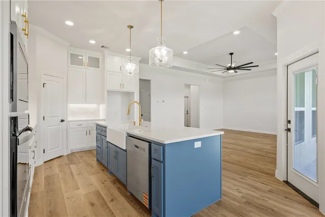 a large white kitchen with a large kitchen island white cabinetry and refrigerator