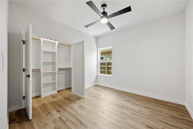a view of empty room with wooden floor and fan
