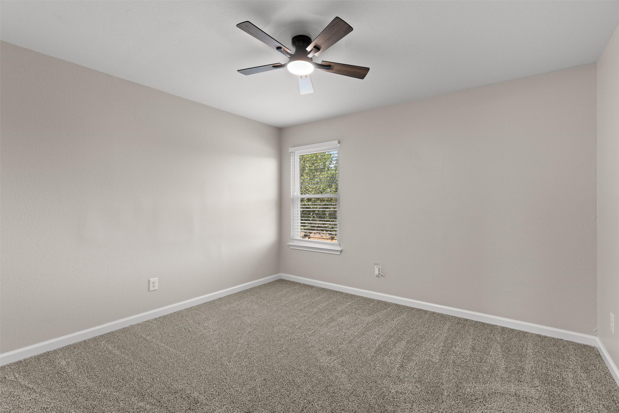 724 Lavaca Loop Elgin, TX 78621 - Photo 27 of 40 Soft carpeting pairs with neutral walls and a window overlooking the outdoor greenery.