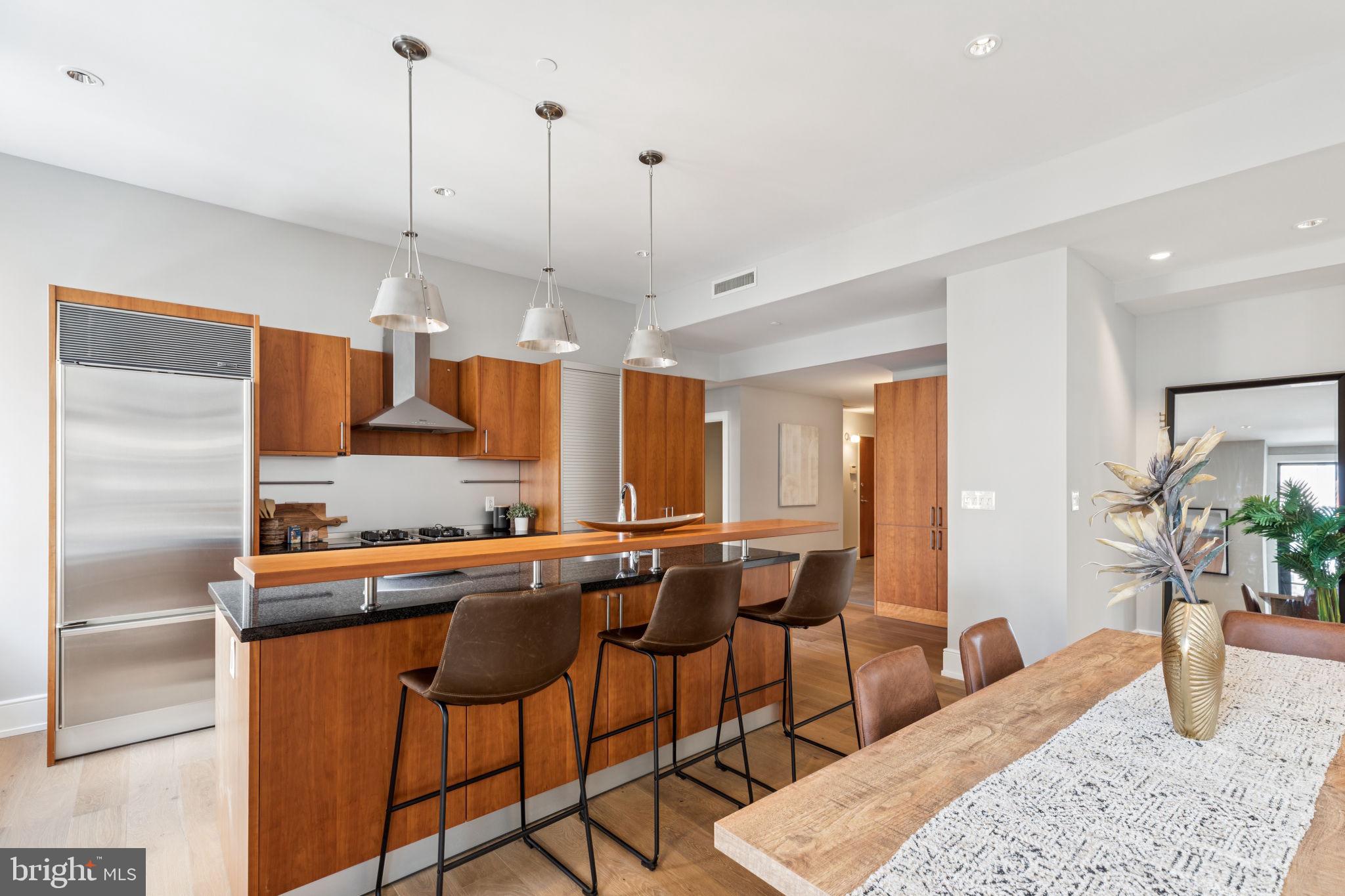 1515 Locust Street, Unit 800 Philadelphia, PA 19102 - Photo 4 of 59 a kitchen with stainless steel appliances kitchen island granite countertop a table chairs in it and wooden floors