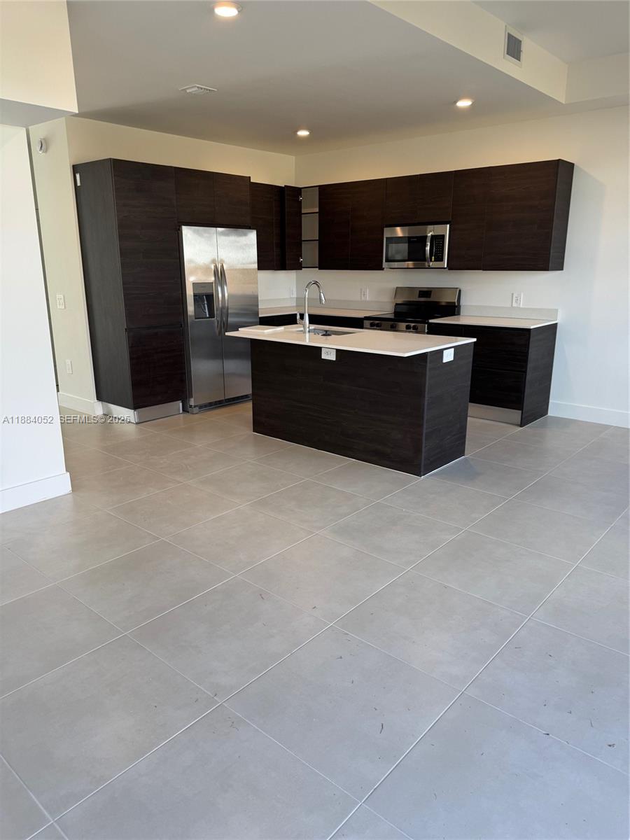 18951 Southwest 344th Terrace Homestead, FL 33034 - Photo 5 of 14 a large kitchen with stainless steel appliances a large counter top a stove a sink a microwave and a refrigerator