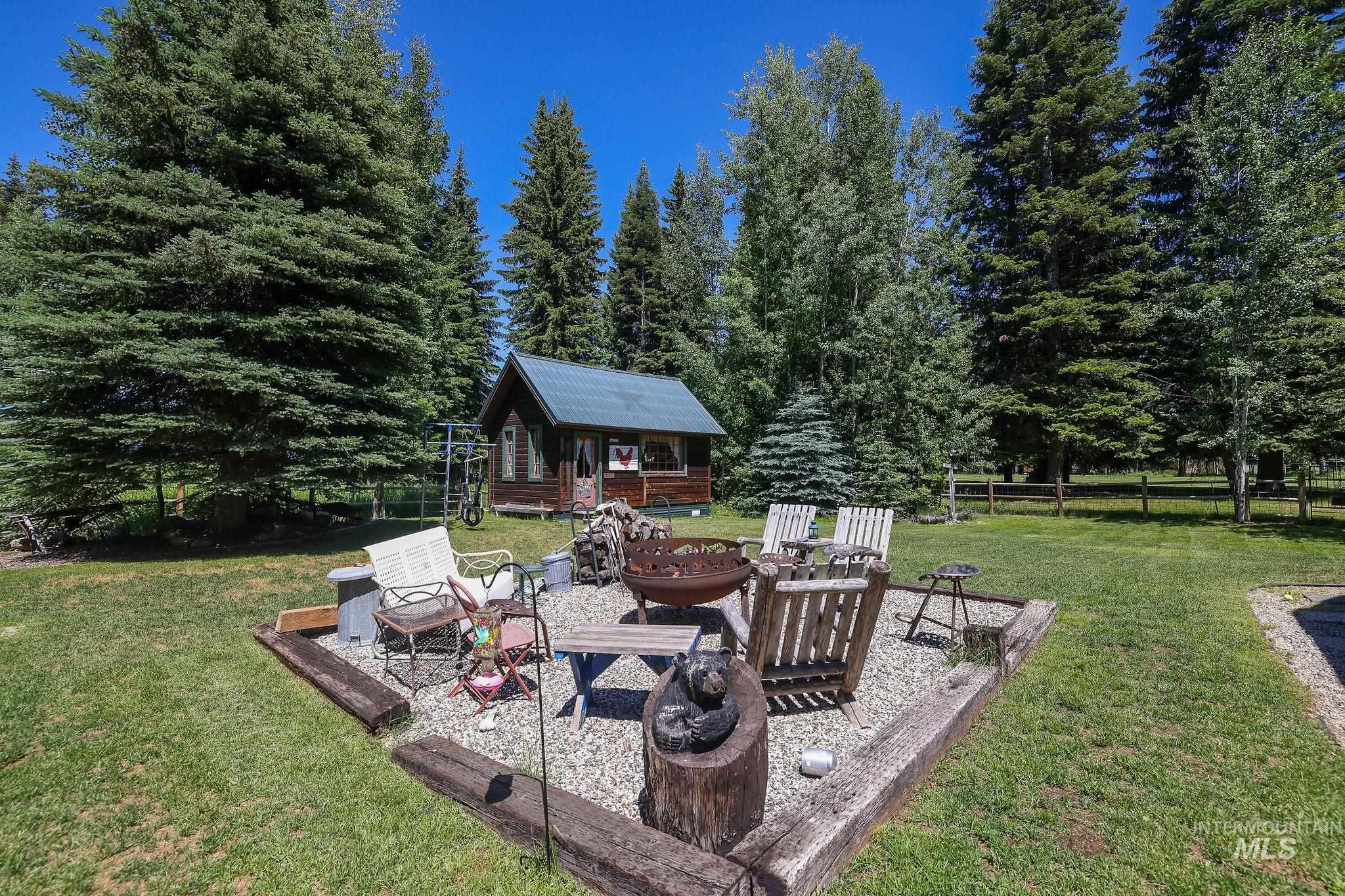 1345 Divot Lane McCall, ID 83638 - Photo 2 of 13 Expansive outdoor area featuring a central fire pit with a gravel base and wood-beam borders