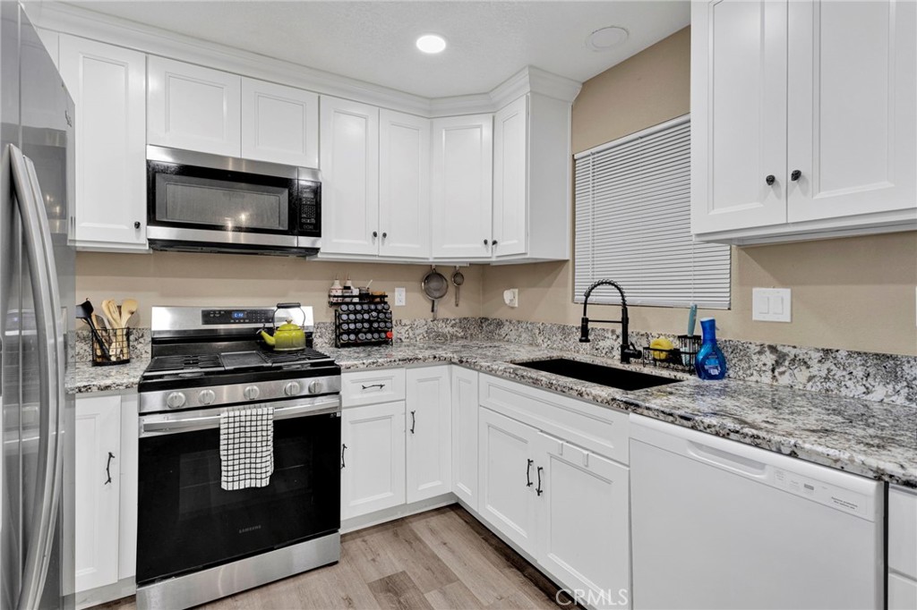 15471 Washoan Road Apple Valley, CA 92307 - Photo 12 of 38 a kitchen with white cabinets and stainless steel appliances